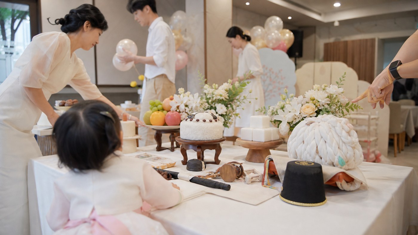Daytime Korean dol table setup with family arranging traditional birthday details